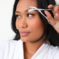 Woman using scissors to trim her eyebrows with a white background